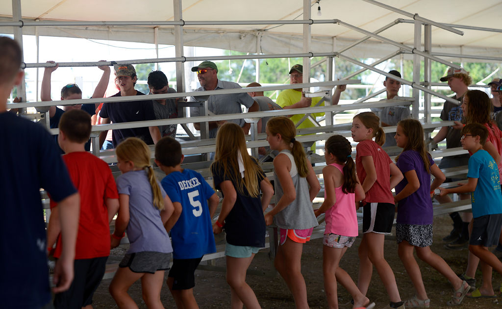 Spectators, volunteers, competitors and their family members help move the bleachers